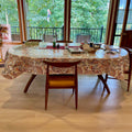 Oval table with floral oilcloth tablecloth in sunlit dining room, Premier Table Linens decor.