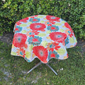 Round outdoor table with vibrant floral oilcloth tablecloth, perfect for events and parties